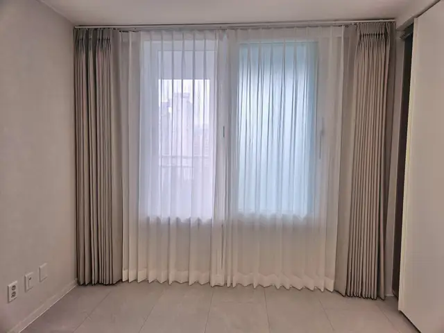 침실 창 전체에 베이지 암막 커튼을 단 모습